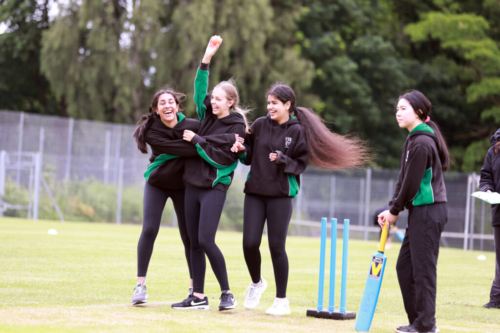 a picture of a group of students lalughing while playing cricket