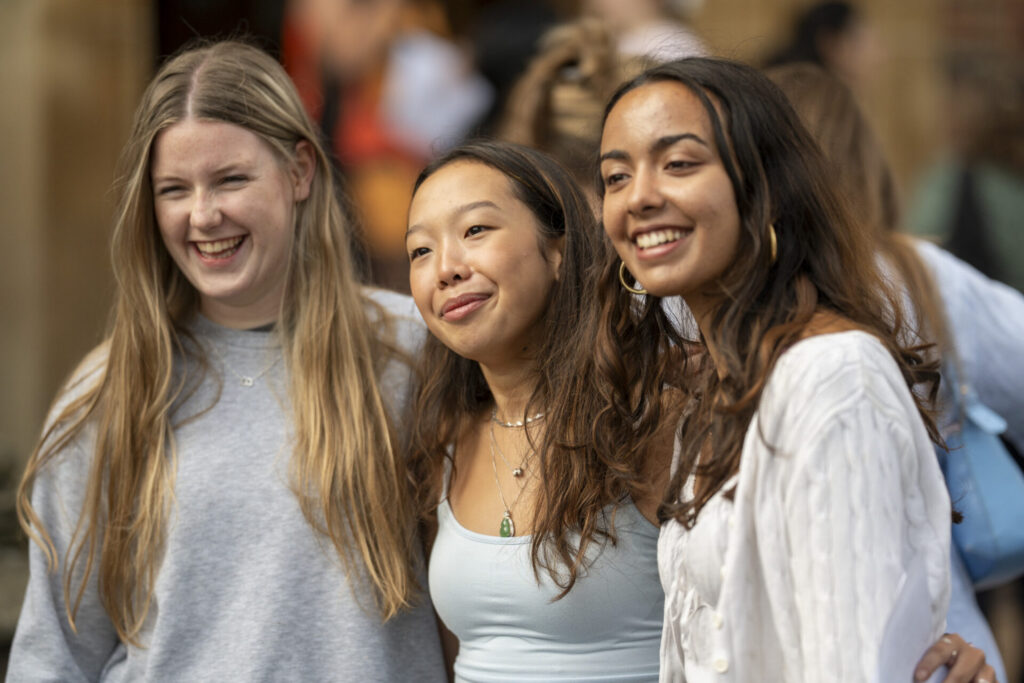 Three young women smiling and looking to the side.